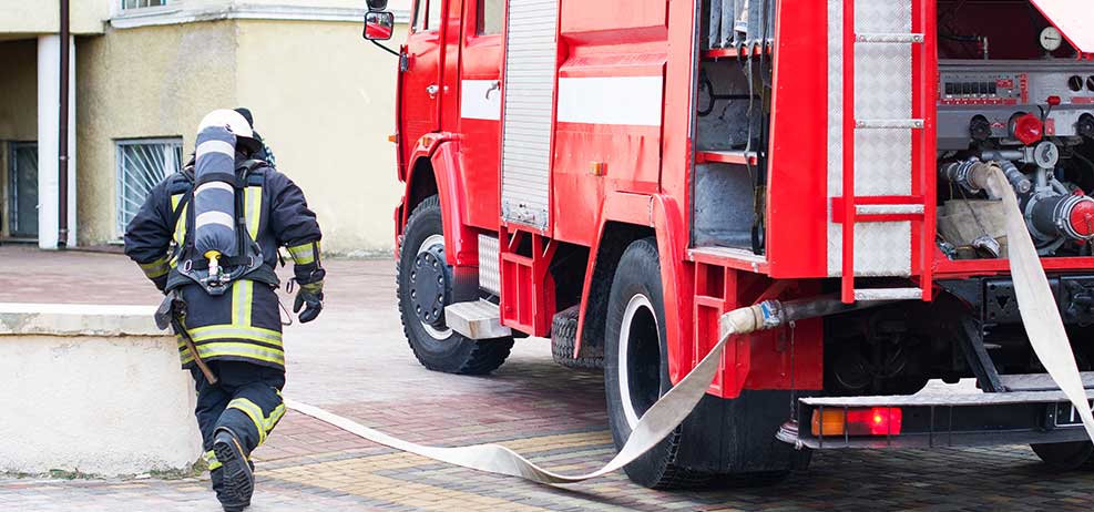 firetruck with firefighter running next to it