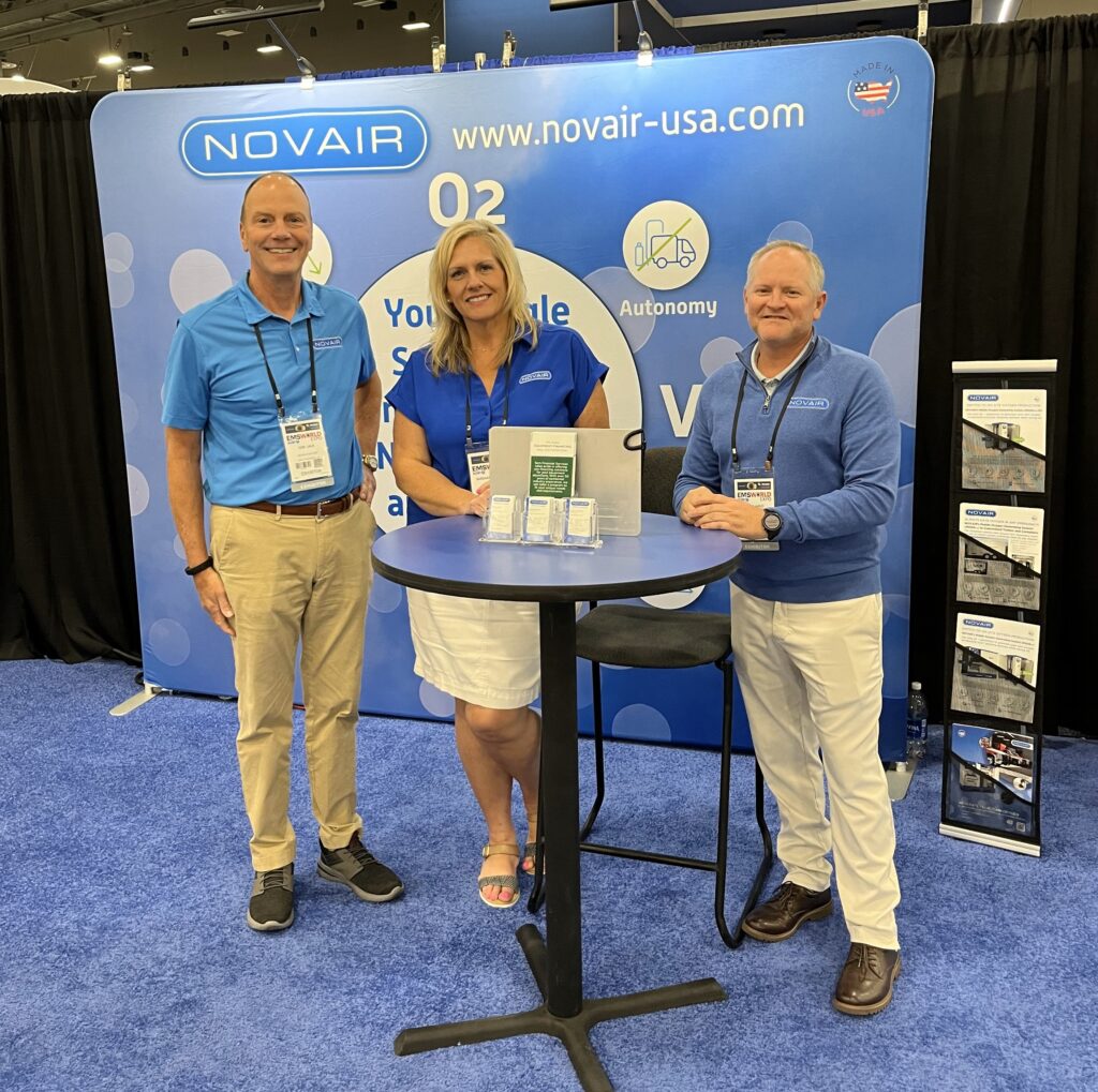 novair display at trade show with three people standing smiling